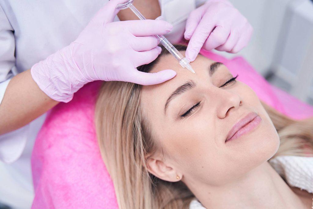 Woman receiving cosmetic injections into middle of brows