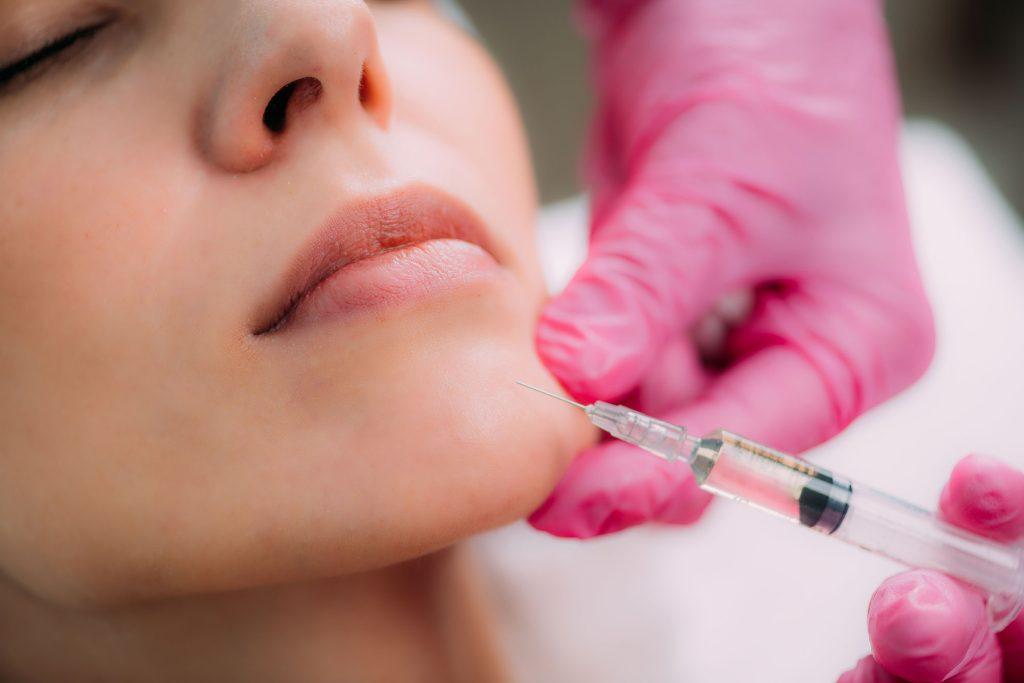 Woman receiving cosmetic injection into chin
