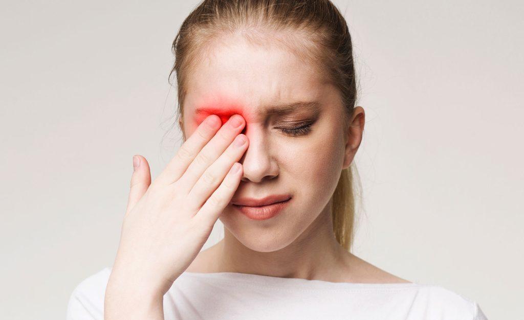 Woman holding her eye in pain, eye injury
